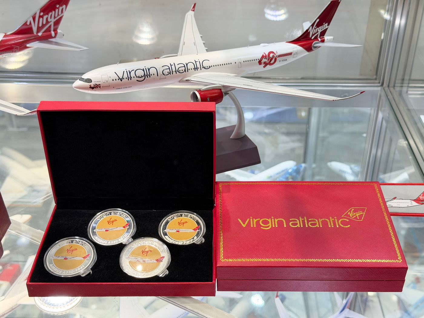 Virgin Atlantic model airplane and collectible coins in a display case.